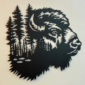 Black metal wall art shaped like a buffalo head with pine tree forest cutout details, mounted on a light wall.