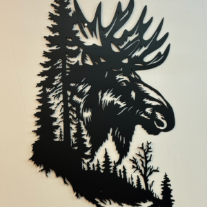 Black metal wall art shaped like a moose with a forest wildlife scene cut into the design, mounted on a light wall.