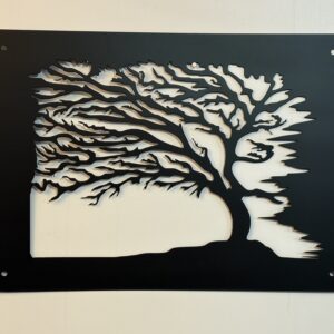 Black metal wall art panel featuring a windblown tree silhouette with layered cutout branches, shown mounted against a light wall with corner mounting holes.
